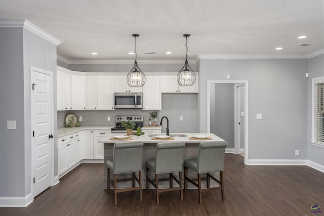 kitchen with sink, a breakfast bar, appliances with stainless steel finishes, white cabinets, and a center island with sink