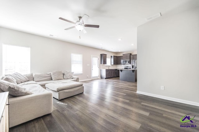 living room featuring ceiling fan, sink, and dark hardwood / wood-style floors