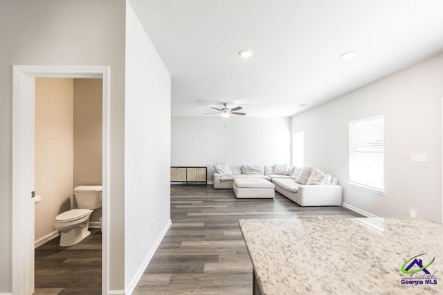 living room with ceiling fan and dark hardwood / wood-style flooring