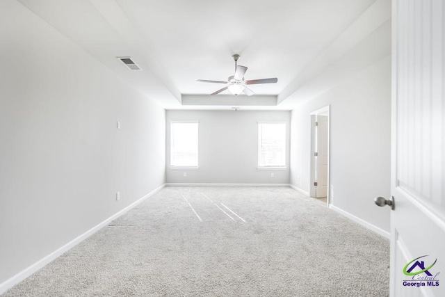 carpeted spare room featuring a raised ceiling and ceiling fan