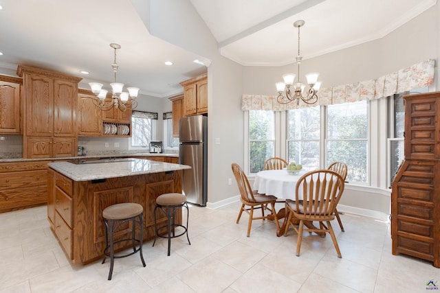 kitchen featuring stainless steel refrigerator, pendant lighting, a kitchen island, and a notable chandelier