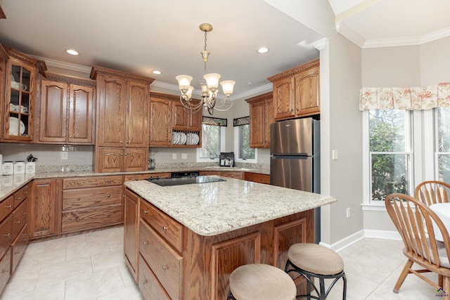 kitchen featuring black electric stovetop, ornamental molding, stainless steel refrigerator, and a center island