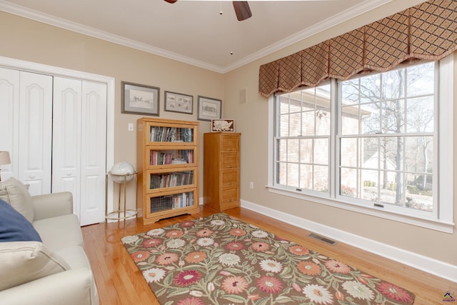 living area with hardwood / wood-style floors, crown molding, a wealth of natural light, and ceiling fan