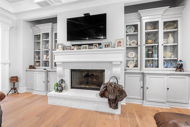 living room featuring a brick fireplace and light hardwood / wood-style flooring