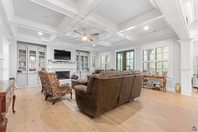 living room featuring beam ceiling, ceiling fan, decorative columns, and light wood-type flooring