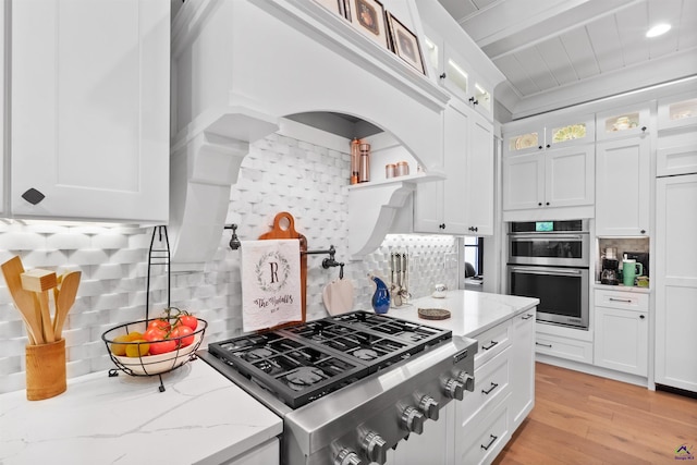 kitchen featuring stainless steel appliances, tasteful backsplash, light stone countertops, and white cabinets