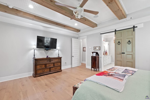 bedroom featuring ensuite bath, a barn door, beam ceiling, and light hardwood / wood-style flooring