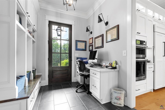 interior space with ornamental molding, built in desk, and dark tile patterned floors