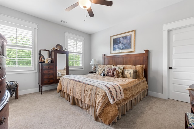 bedroom with ceiling fan, light colored carpet, and multiple windows