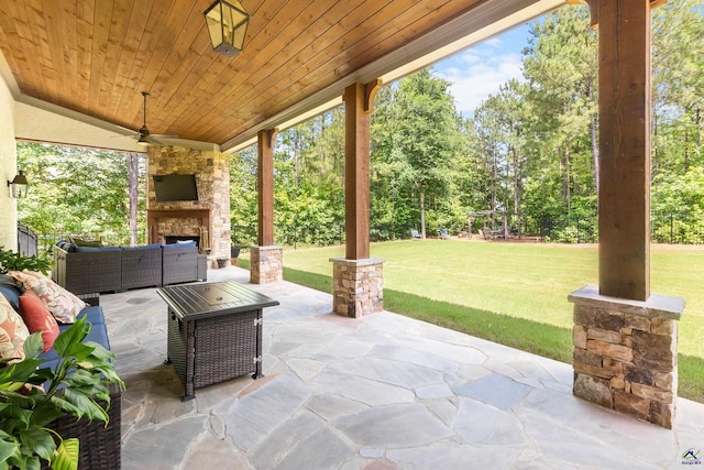 view of patio / terrace with ceiling fan and an outdoor living space with a fireplace