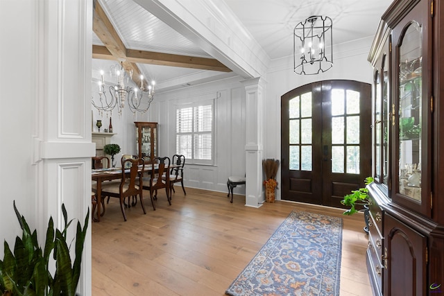 entrance foyer with ornamental molding, light wood-type flooring, an inviting chandelier, and french doors