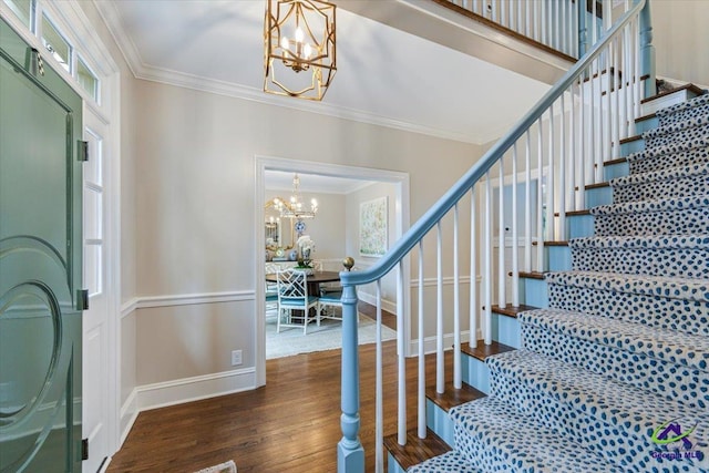 entryway with ornamental molding, dark wood-type flooring, and a chandelier