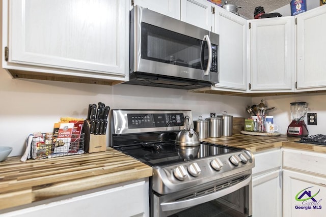 kitchen with white cabinetry, stainless steel appliances, butcher block countertops, and a textured ceiling