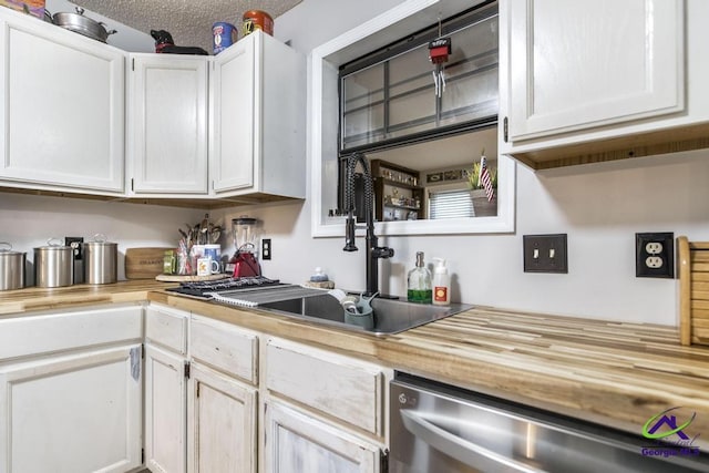 kitchen featuring sink, a textured ceiling, stainless steel dishwasher, and white cabinets