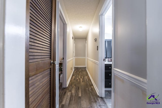 corridor featuring dark wood-type flooring and a textured ceiling