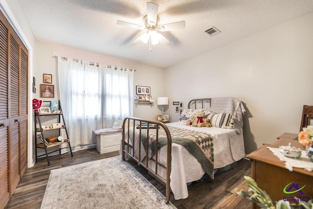 bedroom featuring dark wood-type flooring, ceiling fan, a closet, and a textured ceiling