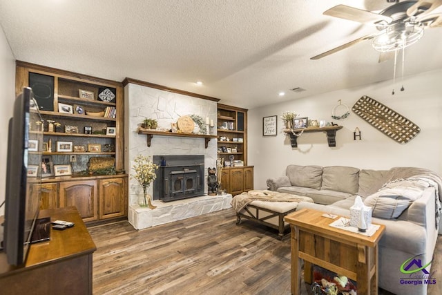 living room featuring ceiling fan, dark wood-type flooring, built in features, and a textured ceiling