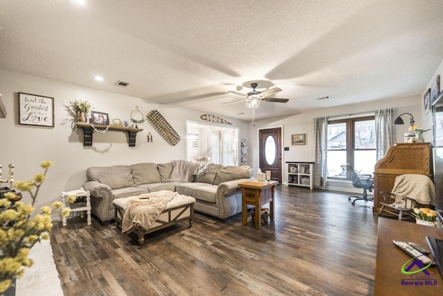 living room with ceiling fan, dark wood-type flooring, and a textured ceiling