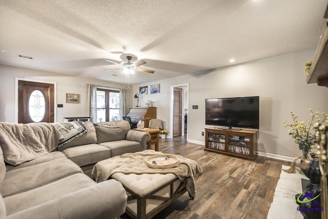 living room featuring dark hardwood / wood-style flooring, ceiling fan, and a textured ceiling