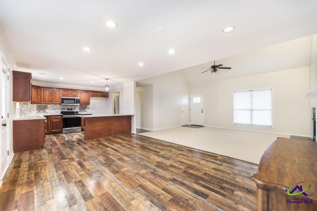 kitchen with sink, hanging light fixtures, a kitchen island, stainless steel appliances, and backsplash