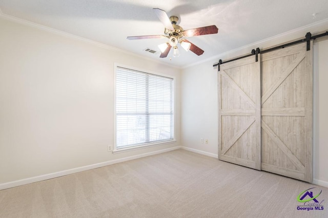 unfurnished bedroom with ornamental molding, a barn door, light colored carpet, and ceiling fan