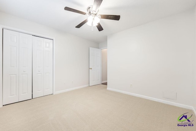 unfurnished bedroom featuring ceiling fan, light colored carpet, and a closet