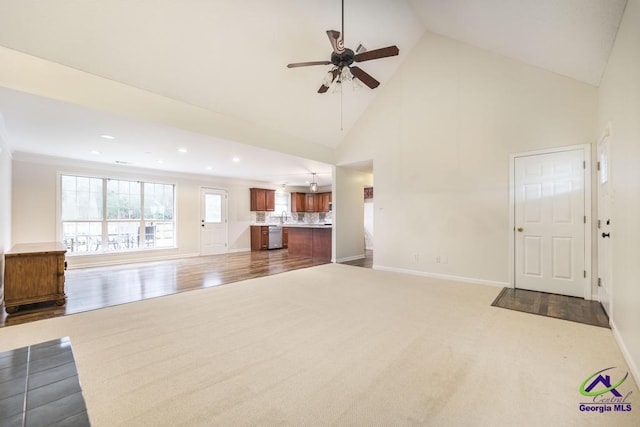 unfurnished living room with ceiling fan, carpet flooring, and high vaulted ceiling