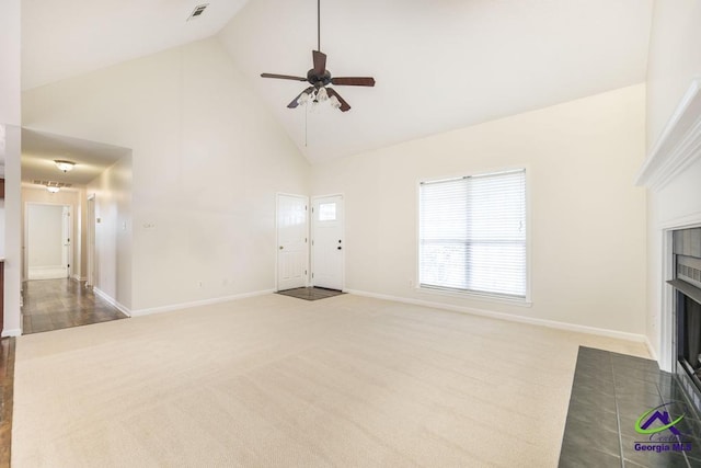 unfurnished living room featuring a tiled fireplace, carpet floors, high vaulted ceiling, and ceiling fan