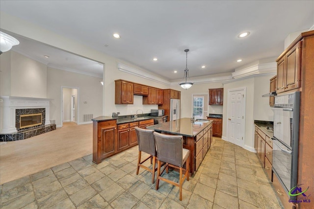 kitchen featuring a high end fireplace, hanging light fixtures, fridge with ice dispenser, and a kitchen island