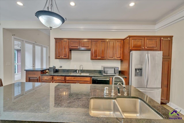 kitchen with dark stone countertops, sink, stainless steel appliances, and hanging light fixtures