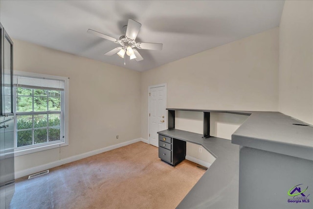 unfurnished office featuring light carpet and ceiling fan