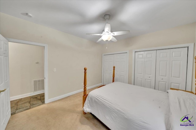 carpeted bedroom featuring multiple closets and ceiling fan