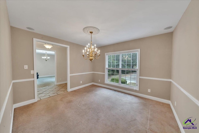 carpeted spare room with an inviting chandelier