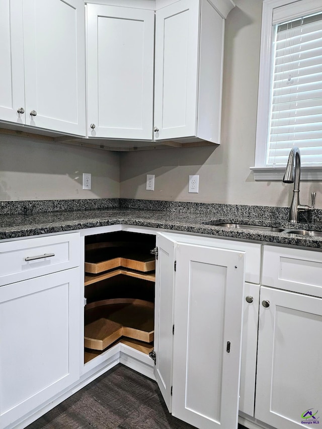 kitchen with sink, dark stone counters, and white cabinets