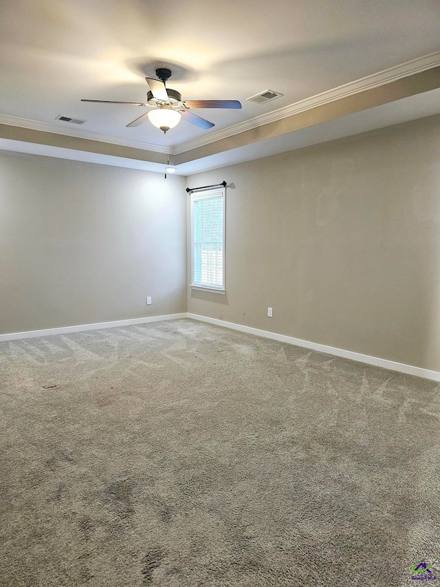 unfurnished room featuring a raised ceiling, ornamental molding, carpet, and ceiling fan
