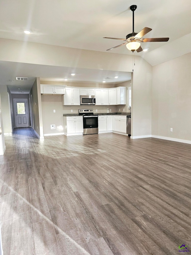 kitchen with white cabinetry, appliances with stainless steel finishes, vaulted ceiling, and hardwood / wood-style flooring