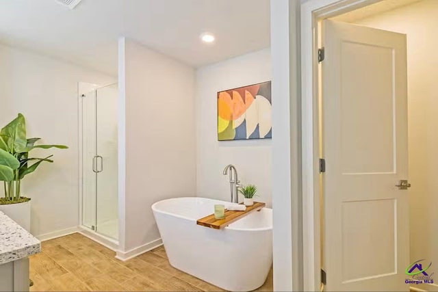 bathroom featuring vanity, hardwood / wood-style flooring, and plus walk in shower