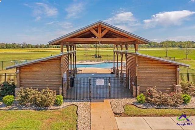 exterior space featuring a rural view, a community pool, a gazebo, and a lawn