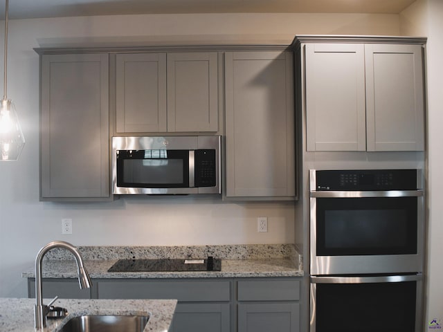 kitchen with light stone counters, appliances with stainless steel finishes, gray cabinets, and sink