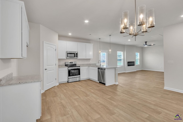 kitchen featuring pendant lighting, white cabinetry, sink, kitchen peninsula, and stainless steel appliances