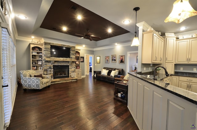 kitchen featuring dark wood-type flooring, a tray ceiling, hanging light fixtures, and dark stone countertops