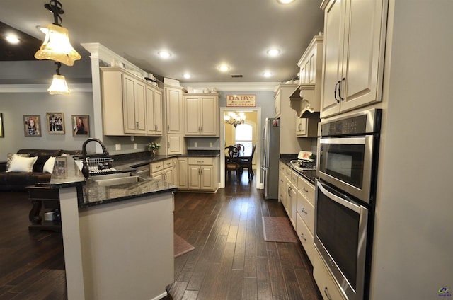 kitchen featuring dark wood-type flooring, a breakfast bar, decorative light fixtures, appliances with stainless steel finishes, and kitchen peninsula