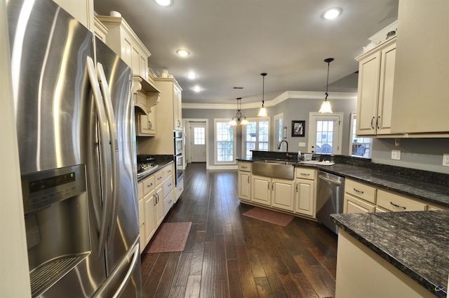 kitchen featuring pendant lighting, cream cabinets, and appliances with stainless steel finishes