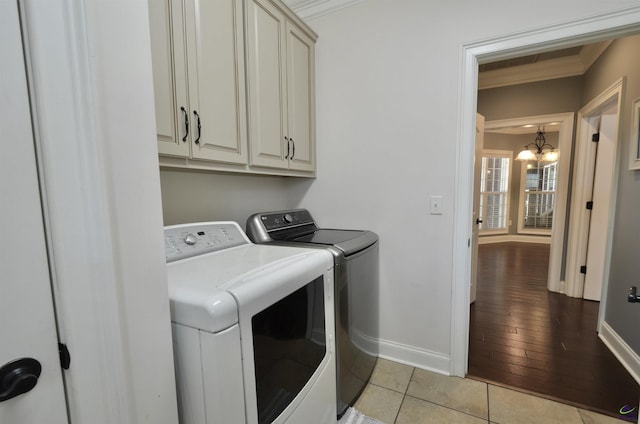 clothes washing area featuring light tile patterned flooring, separate washer and dryer, cabinets, crown molding, and an inviting chandelier