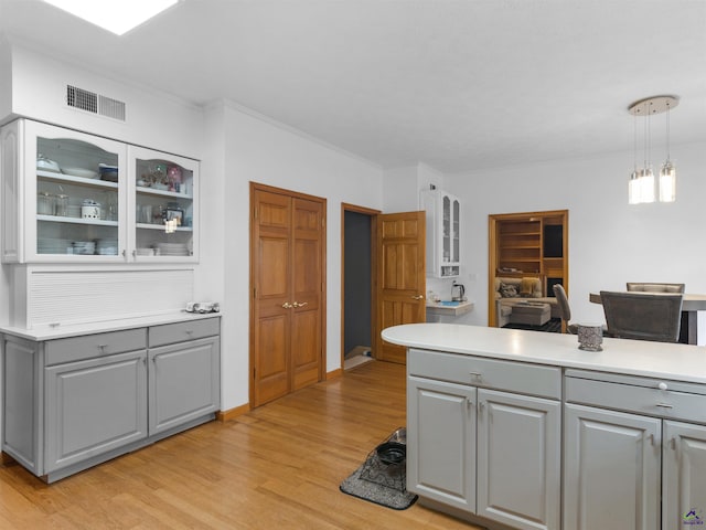 kitchen with crown molding, decorative light fixtures, light hardwood / wood-style flooring, and gray cabinetry