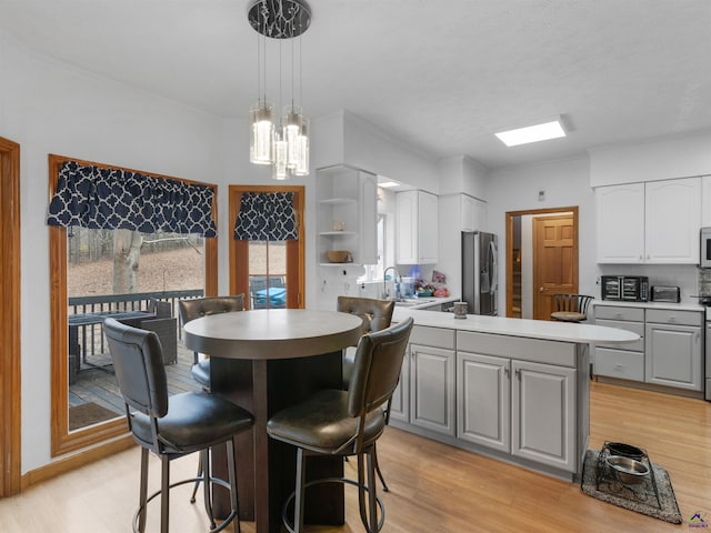 kitchen with stainless steel appliances, decorative light fixtures, gray cabinets, and sink