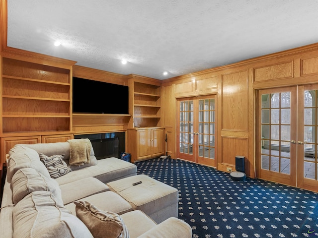 carpeted living room featuring ornamental molding, french doors, a textured ceiling, and wood walls