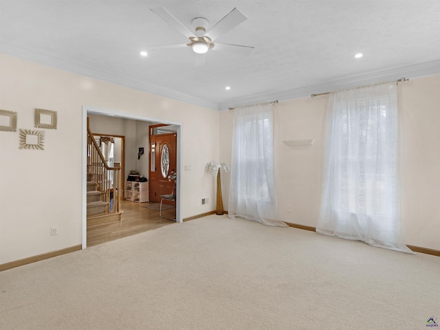 spare room with light colored carpet, ornamental molding, and ceiling fan