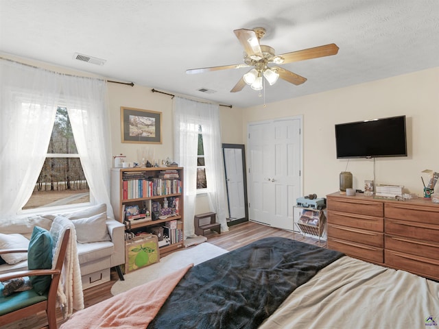 bedroom with multiple windows, ceiling fan, a textured ceiling, and light hardwood / wood-style flooring