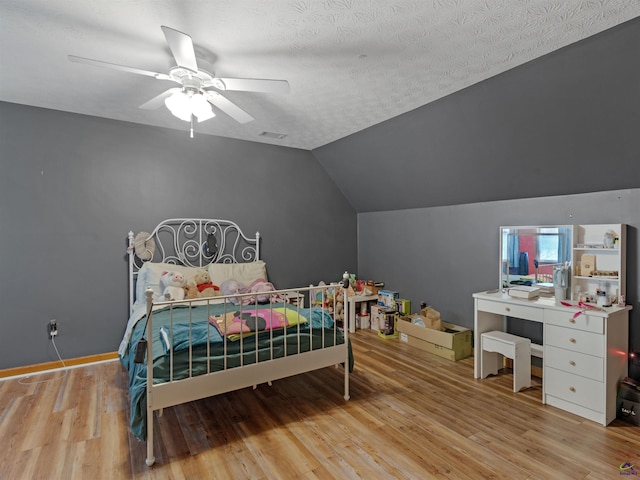 bedroom with vaulted ceiling, ceiling fan, a textured ceiling, and light hardwood / wood-style flooring